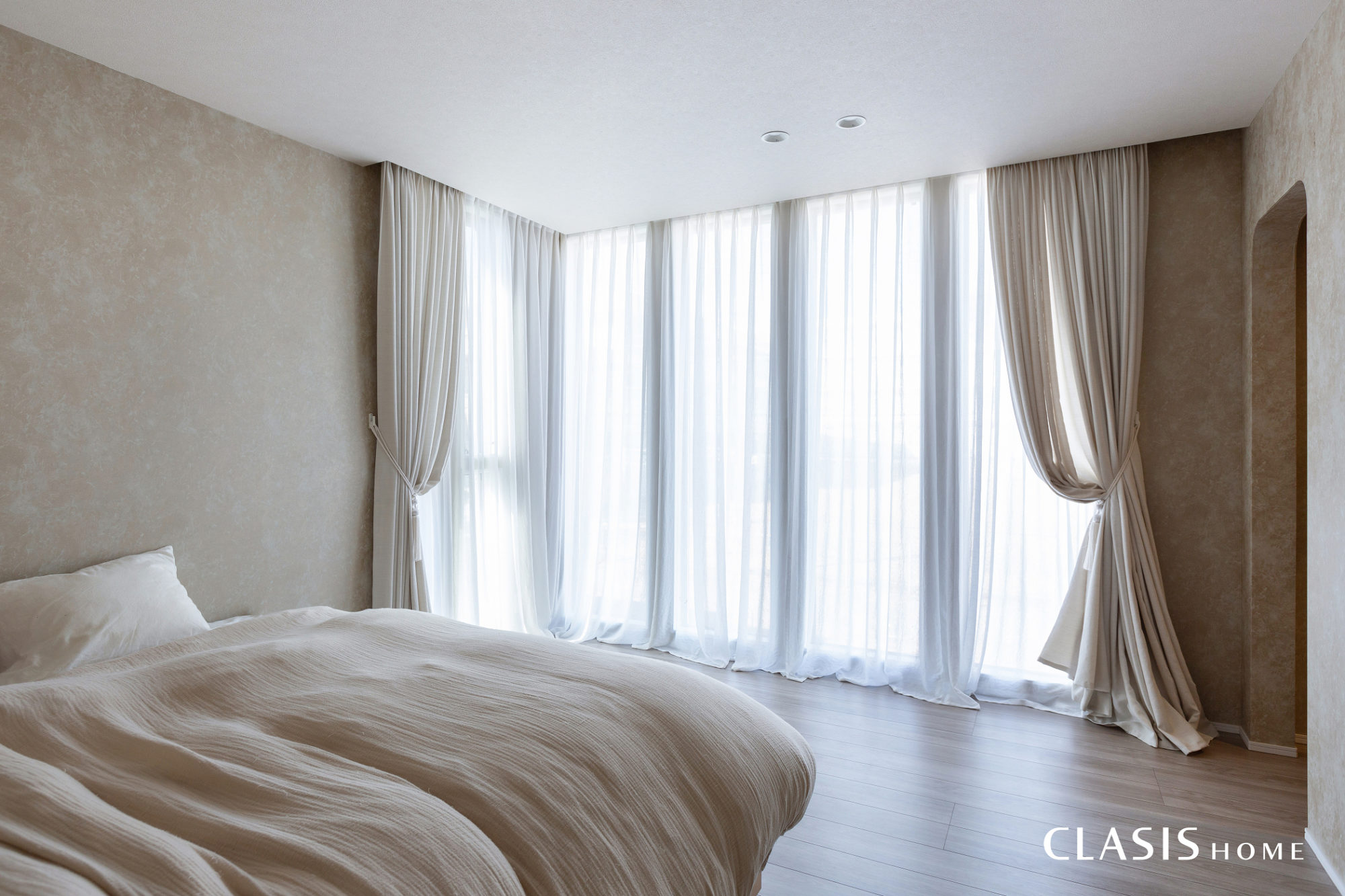 大きな窓から柔らかく陽が差し込む寝室。ベージュで統一した淡いインテリアが癒しの空間を作ります。