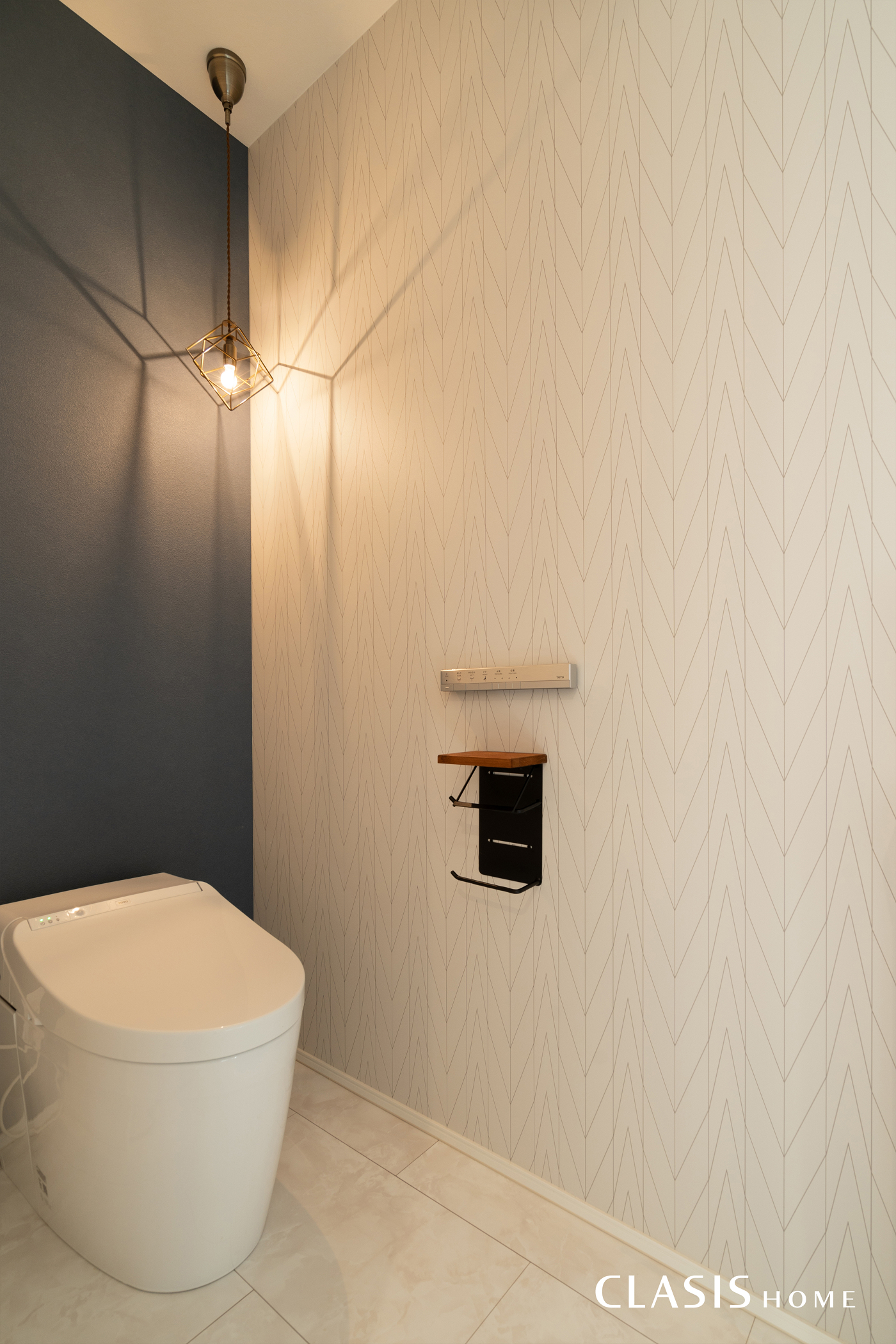 白いヘリンボーン柄と、ネイビーカラーのシンプルなクロスを組み合わせたトイレ。